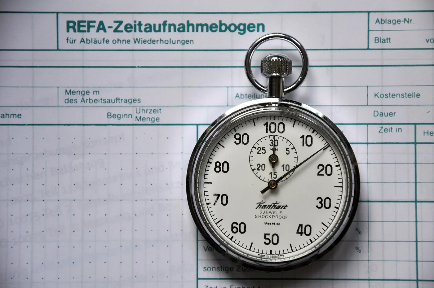 A stopwatch lying on a printed time-study sheet