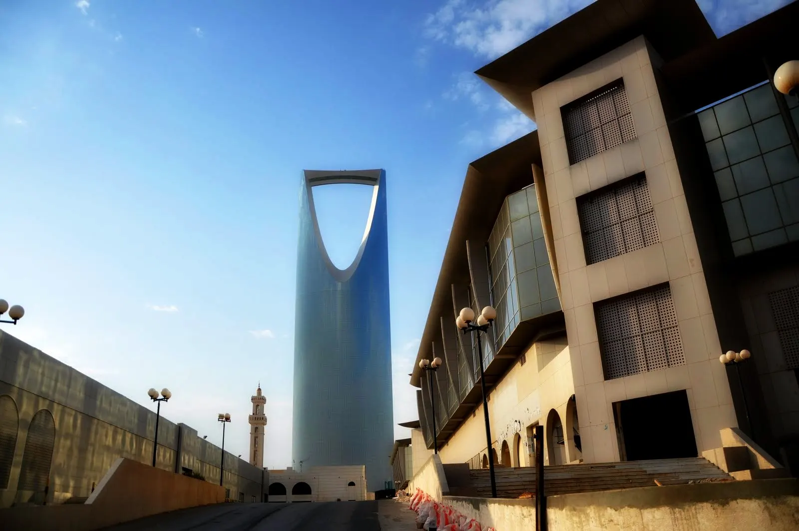 The Kingdom Centre tower and its open arch against a blue sky, seen from a nearby street