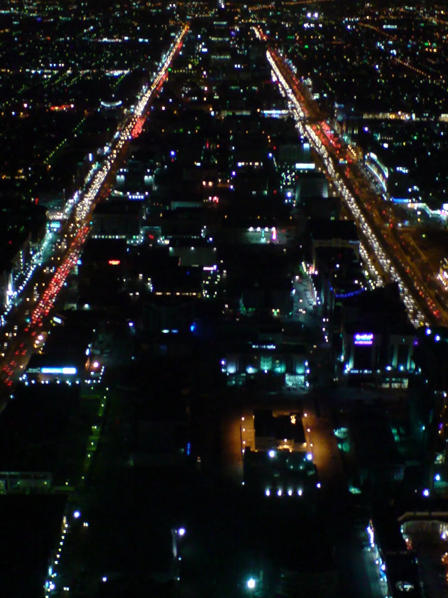 Looking down King Fahd Road from the Kingdom Centre at night, lines of traffic light between dark blocks